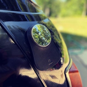 A close-up of a black classic mini cooper featuring a personalized black leather gas tank bib, showcasing a stylish and sophisticated automotive accessory