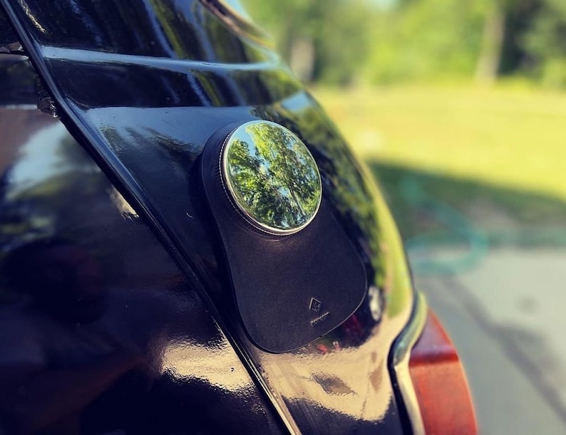 A close-up of a black classic mini cooper featuring a personalized black leather gas tank bib, showcasing a stylish and sophisticated automotive accessory