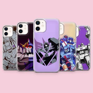 Peut inclure: Cinq coques de smartphone présentant divers designs de personnages Decepticon de Transformers. Les coques affichent des illustrations graphiques de robots dans des tons de violet, gris, bleu et rouge, incluant le logo Decepticon sur fond violet clair.