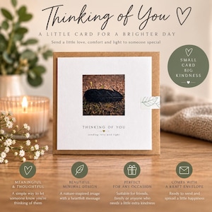 Può includere: Un biglietto d'auguri quadrato con busta in carta kraft che presenta una fotografia centrale di una piuma nera sull'erba. Il biglietto riporta il testo Thinking of You e sending love and light. Un piccolo badge circolare verde a destra recita Small Card Big Kindness.
