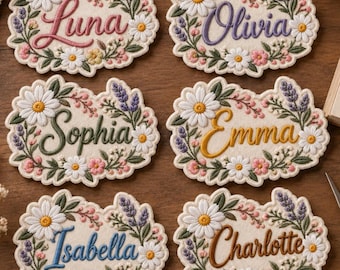 May include: Six oval-shaped embroidered patches featuring floral borders of white daisies, pink flowers, and purple lavender sprigs. Each patch displays a unique name in cursive script: Luna, Olivia, Sophia, Emma, Isabella, and Charlotte.