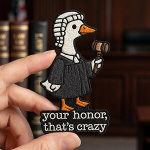 May include: An embroidered patch featuring a white goose wearing a black judicial robe and a white wig, holding a brown wooden gavel. Below the goose, a black rectangular patch displays the white text: your honor, that's crazy.