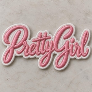 May include: An embroidered patch featuring the word Pretty Girl in a cursive script font. The lettering is stitched in a vibrant pink thread with a thick white border outline, creating a raised texture against the fabric base of the patch.