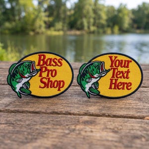 May include: Two oval embroidered patches featuring a green and white fish graphic on a yellow background with a black border. The left patch displays the red text Bass Pro Shop, while the right patch displays the red text Your Text Here.