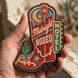 May include: An embroidered patch shaped like a cowboy boot with a red base, featuring a yellow crescent moon, a green cactus, and a blue star. The text Midnight RODEO is stitched in white, with a vertical teal sign reading MOTEL in yellow letters.