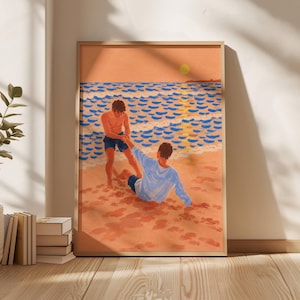 以下が含まれることがあります： 夕暮れのビーチを描いた額装アートプリント。砂浜には2人の人物がおり、1人はダークブルーのショートパンツを履いて立ち、もう1人はライトブルーの長袖シャツとダークブルーのショートパンツを着用して砂浜に座り、海辺の風景が広がっています。