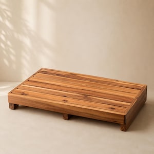 May include: A rectangular wooden platform constructed from several horizontal slats of natural brown wood with visible grain patterns. The platform features a low-profile design supported by small, sturdy feet at each corner and along the sides.