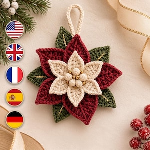 May include: A crocheted poinsettia ornament featuring layered dark red and green leaves with a cream-colored center. The flower is accented with small gold beads and a cream-colored loop at the top for hanging, crafted with intricate yarn textures.