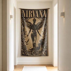 May include: A rectangular woven wall tapestry featuring the word NIRVANA in bold capital letters at the top. The design depicts a central winged figure surrounded by intricate illustrations of roses, candles, stars, and crescent moon symbols in black and tan.