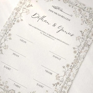 Può includere: Un certificato rettangolare Dini Nikah Belgesi con i nomi Dilhan & Yunus in calligrafia nera. Il documento include campi per Gelin, Damat, Imam, Mehir, Sahit e Tarih, incorniciato da un delicato bordo di viticci floreali grigio chiaro.