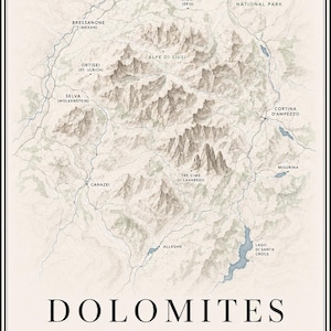 Op de afbeelding: Een topografische kaart van de Dolomieten in Italië, met bergketens, rivieren en gelabelde steden zoals Brunico, Ortisei en Cortina d'Ampezzo. De print bevat een windroos, de tekst DOLOMITES ITALY en de coördinaten 46.5170 N, 12.1000 E.