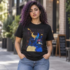 Peut inclure: Un t-shirt noir à manches courtes avec une impression graphique représentant une figure céleste à tête de croissant de lune assise sur une planète. Le motif inclut le texte "HYLICS" en lettres blanches, entouré d'étoiles, d'un éclair et d'éléments cosmiques colorés.