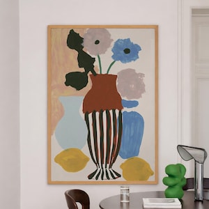 May include: A framed wall art print featuring a central terracotta vase with black vertical stripes containing flowers. The composition includes a light blue vase, a solid blue vase, two yellow lemons, and abstract floral shapes in muted tones.