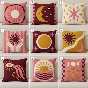 Puede incluir: Un conjunto de nueve cojines cuadrados con diversos diseños celestiales y botánicos en tonos rosa, granate y amarillo mostaza. Cada cojín muestra ilustraciones gráficas únicas que incluyen soles, lunas, estrellas, ojos y patrones florales.