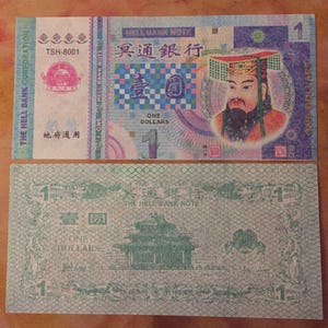 May include: A green and white paper bank note with the text "The Hell Bank Note" and "One Dollars" printed on it. The note features a green image of a building with a roof and a red and white image of a person with a crown.