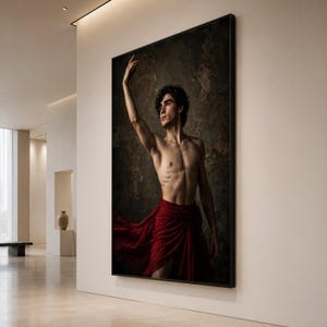 May include: A large framed wall art print featuring a portrait of a person with dark curly hair, posing with one arm raised. The person is shirtless and wearing a flowing, deep red fabric draped around the waist against a dark, textured background.