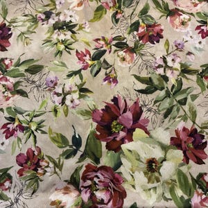 May include: A fabric featuring a floral pattern on a beige background. The design includes large, deep burgundy and white peony-like flowers, smaller light pink blossoms, and various green leaves, all rendered in a painterly style with fine lines.