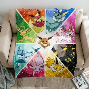 May include: A soft fleece throw blanket featuring a central Eevee surrounded by eight colourful triangular panels, each displaying a different Eevee evolution including Flareon, Vaporeon, Sylveon, Glaceon, Espeon, Jolteon, Umbreon, and Leafeon.