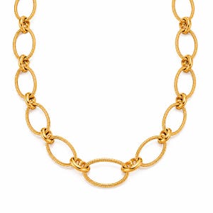 Puede incluir: Un collar de tono dorado que presenta una serie de eslabones ovalados interconectados. Cada eslabón individual muestra un patrón de superficie texturizado similar a una cuerda, creando un diseño consistente a lo largo de la cadena.
