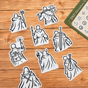 May include: A collection of eight black and white stickers featuring fantasy character illustrations, including figures with axes, swords, staves, torches, and musical instruments, alongside a partial DND Adventure Icons game board sheet.