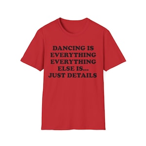 Könnte beinhalten: Ein leuchtend rotes Kurzarm-T-Shirt mit schwarzem Text auf der Vorderseite, der lautet: DANCING IS EVERYTHING EVERYTHING ELSE IS... JUST DETAILS. Das Kleidungsstück hat einen klassischen Rundhalsausschnitt und einen geraden Saum.