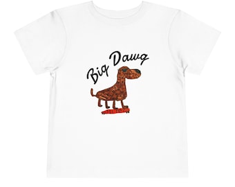 May include: A white short-sleeve t-shirt featuring a graphic of a brown dog wearing sunglasses while standing on a red skateboard. Above the dog, the text Big Dawg is printed in a black, handwritten-style font. The dog's body is textured.