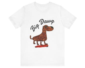 May include: A white short-sleeve t-shirt featuring a brown dog illustration wearing sunglasses and standing on a red skateboard. Above the dog, the text "Big Dawg" is printed in black script. The design is centered on the front of the shirt.