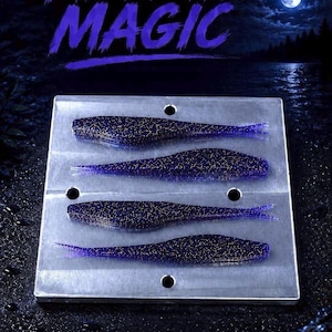 May include: A rectangular metal mold featuring four cavities shaped like small fish lures. Each cavity contains a dark purple, glitter-infused soft plastic fishing bait. The text MIDNIGHT MAGIC is displayed in purple above the metal mold.
