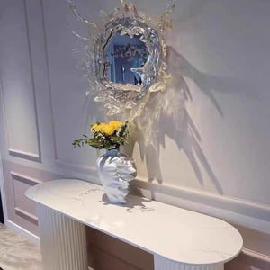 Silver water splash mirror wall light showing the stainless steel body, acrylic mirror, irregular splash silhouette, and illuminated outer edge.