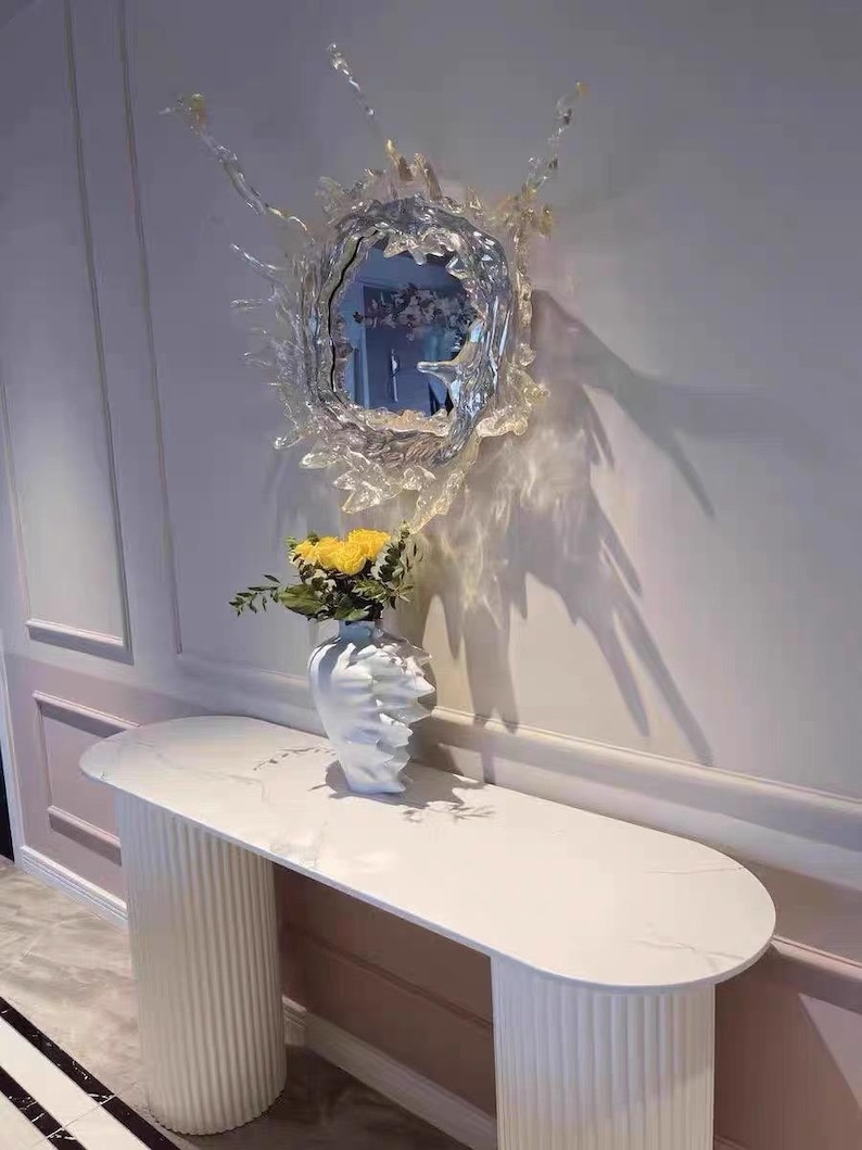 Silver water splash mirror wall light showing the stainless steel body, acrylic mirror, irregular splash silhouette, and illuminated outer edge.