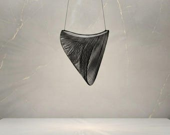 Könnte beinhalten: Eine schwarze Pendelleuchte mit einer konischen, offenen Rahmenstruktur, die aus zahlreichen dünnen, parallelen, drahtartigen Elementen besteht. Das Objekt ist an zwei dünnen schwarzen Kabeln von der Decke abgehängt und bildet eine geometrische, hohle Form.