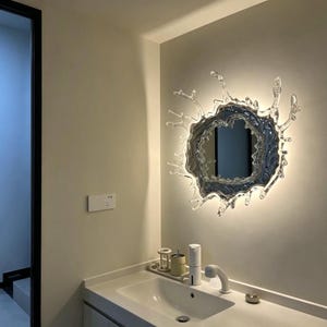 Water splash mirror wall light with an irregular frozen-splash silhouette, reflective acrylic mirror center, stainless steel body, and integrated LED illumination.