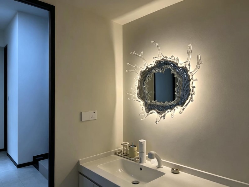 Water splash mirror wall light with an irregular frozen-splash silhouette, reflective acrylic mirror center, stainless steel body, and integrated LED illumination.