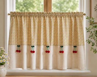 Könnte beinhalten: Ein Scheibengardinen-Vorhang mit gelb-weißem Karomuster in der oberen Hälfte und einer einfarbigen beigen unteren Hälfte. Der Vorhang ist mit fünf Paaren kleiner roter Pompon-Kirschen mit grünen Stielen in einer horizontalen Reihe verziert.