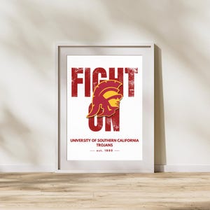May include: A framed wall art print featuring the text FIGHT ON in distressed red lettering. Centered is a yellow and red Trojan helmet graphic. Below, the text reads UNIVERSITY OF SOUTHERN CALIFORNIA TROJANS and est. 1880 in red.