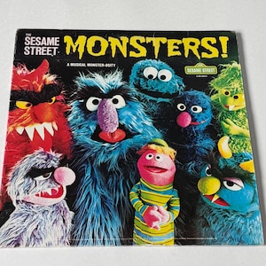 May include: A square vinyl record cover titled The Sesame Street Monsters! A Musical Monster-osity. The cover features a group of colorful, furry monster puppets in shades of red, blue, pink, and green against a black background.