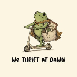 May include: A green frog wearing a patterned cape and riding a kick scooter while carrying a beige tote bag filled with a framed picture and books. The text WE THRIFT AT DAWN is printed in black below the frog on a light cream background.
