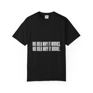 May include: A black short-sleeved t-shirt featuring white text centred on the chest that reads: NO IDEA WHY IT WORKS. NO IDEA WHY IT BROKE. The garment has a crew neckline and a standard fit, with a small brand label visible at the inner collar.