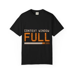 Op de afbeelding: Een zwart t-shirt met korte mouwen en de tekst CONTEXT WINDOW FULL in oranje, verweerde letters. Onder de tekst staat een voortgangsbalk met het getal 100% aan het einde, wat een volledig voltooide status op de borst aangeeft.