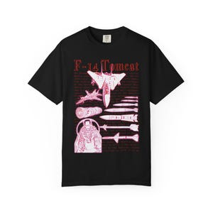 Könnte beinhalten: Ein schwarzes Kurzarm-T-Shirt mit einem roten Grafikdruck eines F-14 Tomcat-Kampfjets, verschiedenen Raketen, einem Strahltriebwerk und Cockpit-Instrumenten. Der Text F-14 Tomcat ist oben aufgedruckt, mit Hintergrundtext zur Geschichte.