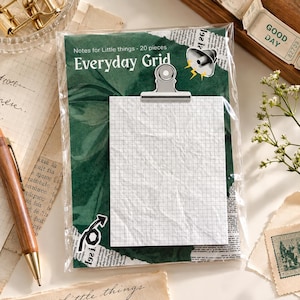 May include: A pack of 20 Everyday Grid notes featuring a dark green background with newspaper print accents, a megaphone graphic, and a silver metal clip holding a white grid-patterned paper sheet in a clear plastic sleeve.