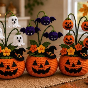 May include: Three crocheted Halloween planters, each featuring a round orange pumpkin base with a black jack-o'-lantern face. The planters are topped with green stems, orange flowers, and small black witch hats, plus white ghosts, purple bats, or orange pumpkins.