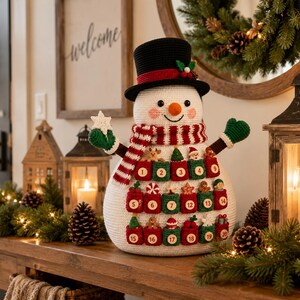 May include: A crocheted snowman advent calendar featuring a black top hat, a red and white striped scarf, and green mittens. The snowman body has twenty small numbered pockets in red and green, each containing a miniature holiday-themed ornament.