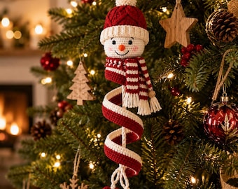 May include: A crocheted snowman ornament featuring a red and white knit hat, a matching striped scarf, and a long, spiraling red and white body that ends in two small, dark red crocheted hearts, all suspended by a white string loop.