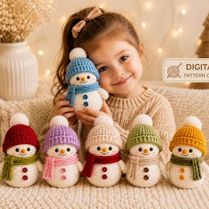 Peut inclure: Une collection de six bonhommes de neige au crochet, chacun portant un bonnet et une &eacute;charpe en tricot de couleurs diff&eacute;rentes avec un pompon blanc. Les bonhommes ont un nez orange et deux boutons. Une &eacute;tiquette indique DIGITAL PATTERN ONLY.
