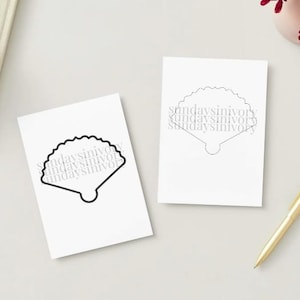 May include: Two white rectangular cards featuring a black outline of a scallop shell. The text "sundaysinivory" is repeated in a light gray font across the center of each shell illustration. The cards are displayed on a neutral surface.