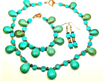 May include: A turquoise jewelry set featuring a necklace, bracelet, and earrings. The necklace and bracelet have teardrop-shaped turquoise stones and round turquoise beads. The earrings have turquoise beads and copper-colored accents. The set is displayed on a white background.