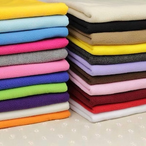 May include: Two stacks of folded fleece fabric in a wide variety of solid colours including yellow, light blue, bright blue, hot pink, grey, light pink, royal blue, lime green, purple, white, orange, cream, black, tan, lavender, brown, red, and maroon.
