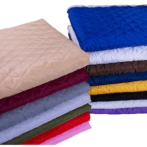 May include: A stack of folded fabric squares featuring a diamond-shaped quilted pattern. The collection includes various solid colors such as beige, burgundy, gray, olive green, red, pink, royal blue, white, brown, navy, yellow, black, and purple.