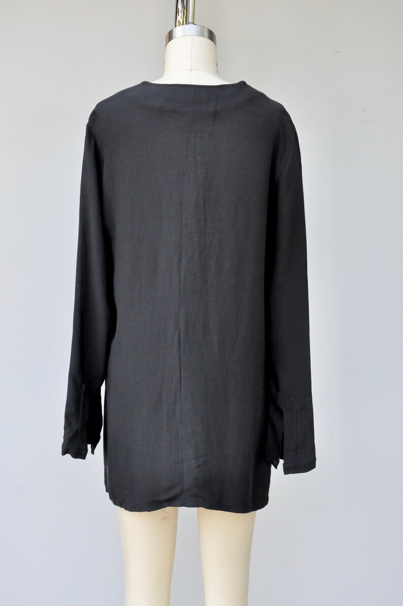 May include: A black long-sleeved shirt with a V-neck and a relaxed fit.